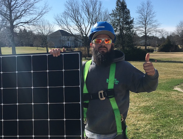 A professional solar panel installer giving a thumbs up at the camera